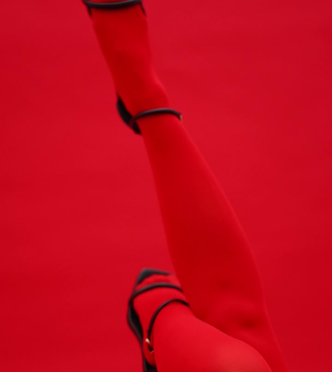 穿着高跟鞋和红色紧身衣的模特的腿挂了起来。垂直视频。
