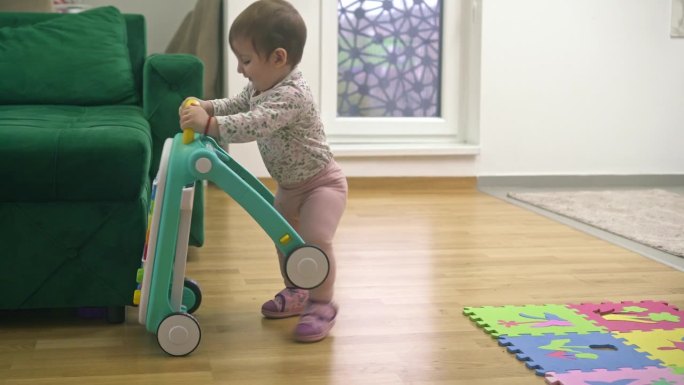一个可爱的小女孩在家里玩玩具学步车