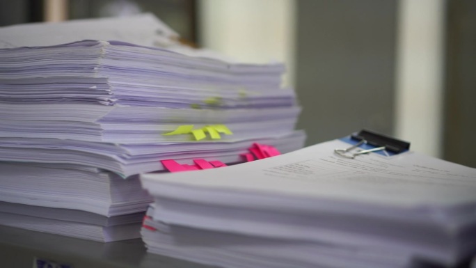 未完成的堆叠税务文件为正在处理报告文件的会计存储文件，在办公桌上有过多的计划，等待管理层批准信息，库