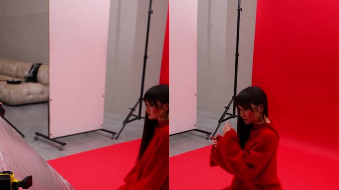 一名亚洲女孩在摄影棚里对着一名摄影师和一名拿着反光镜的助手摆姿势。艺妓女孩360度相机旋转。垂直视频