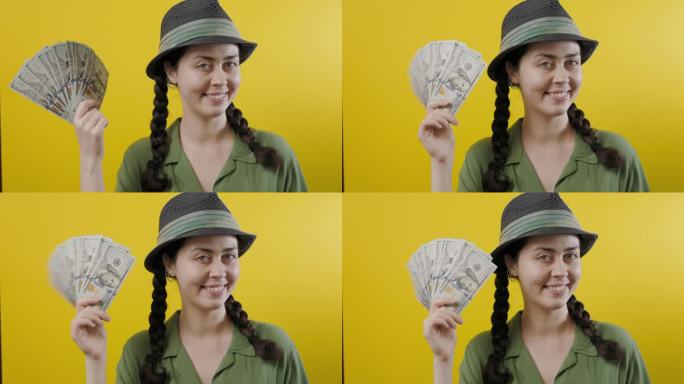 财富和投资。一个戴着草帽的快乐的白人妇女的肖像，展示了一个美元的扇子。黄色背景。彩票中奖的概念