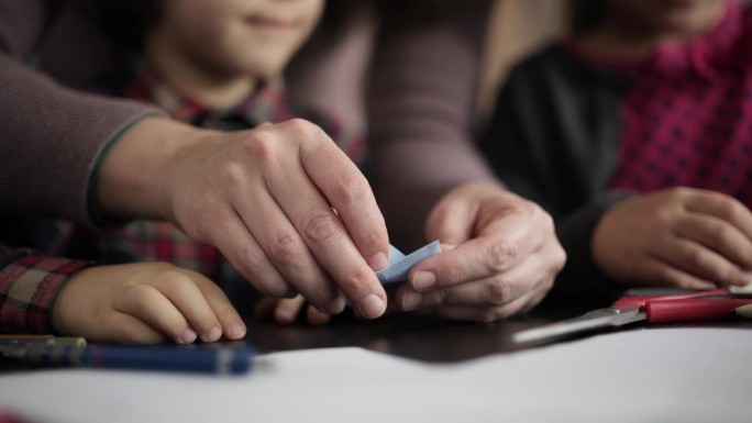 孩子们和妈妈用彩色纸做折纸玩具，按照数码平板电脑视频教程中指示的步骤