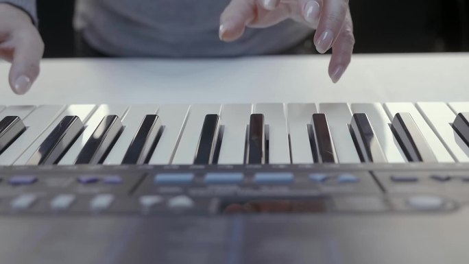 女性的手在合成器键盘上弹奏(钢琴)
