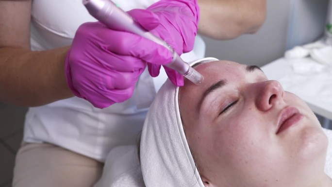 美容师在水疗中心为年轻女性的面部和脸颊注射美沙疗法。病人接受针疗，皮肤护理。水平慢动作