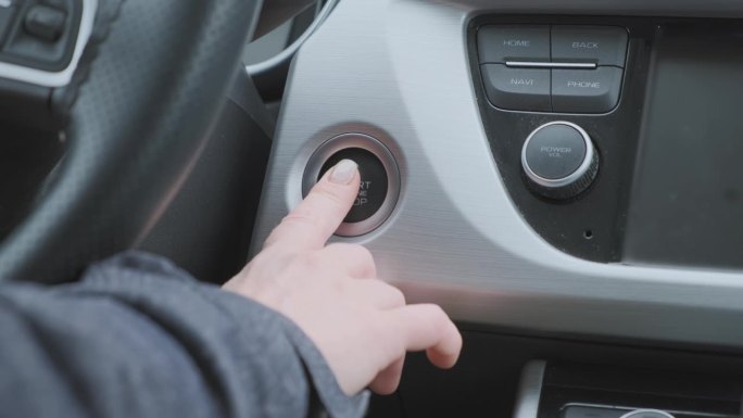 女司机启动或停止汽车发动机，将手指按在启动按钮上
