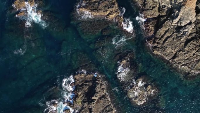 无人机俯瞰海浪冲击小岩石岛屿的画面