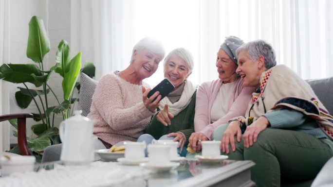 电话，社交媒体和年长的女性朋友在家里的客厅一起参加茶话会。微笑，退休和一群老人一起坐在沙发上边笑边聊