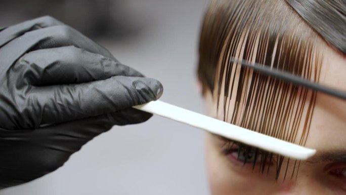 专业的理发师会一丝不苟地为顾客理发，精确地梳理和剪发。特写镜头在现代沙龙捕捉造型师的技术，专注于修饰