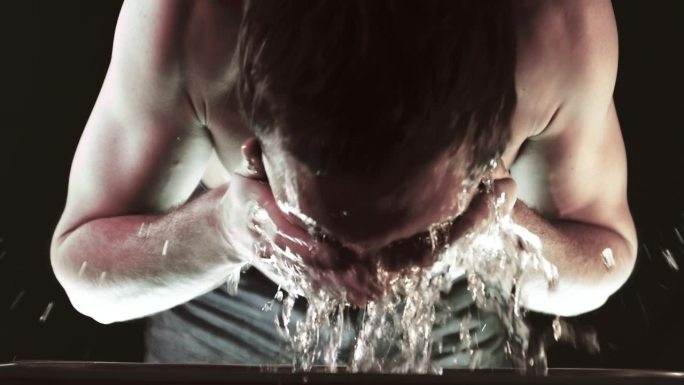 紧张的年轻人用水洗脸。试图恢复理智。往他脸上泼水。