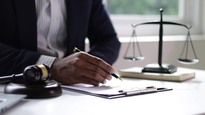 法律公正理念，律师在办公室做文书工作，阅读合同协议和签署文件。