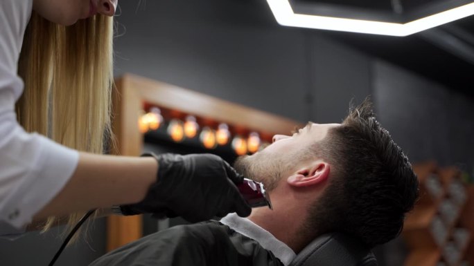 在现代沙龙里，专业理发师给男顾客理发。专业的发型师用剪子、剪刀为时髦的男士做发型。仪容整洁，理发精准