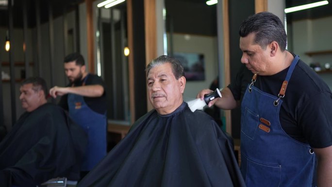 一位理发师在理发店服务后清理老人的画像