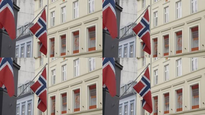 去挪威旅游。行动。狭窄的街道上有两面挪威的红旗。
