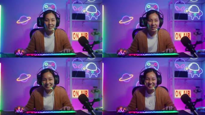 快乐的亚洲女性玩家戴着耳机比赛玩视频游戏与电脑在客厅彩色霓虹灯在线