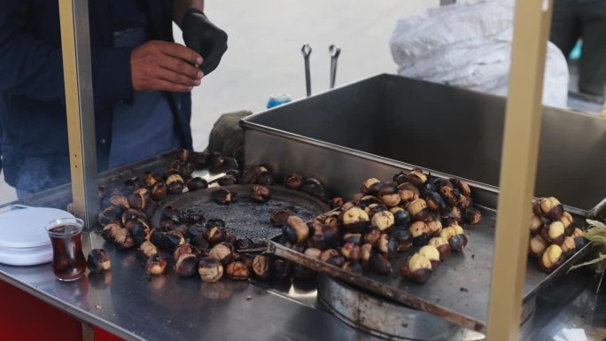 一名土耳其男子开着街头马车向游客兜售烤栗子和煮玉米棒——街头小吃和旅游理念