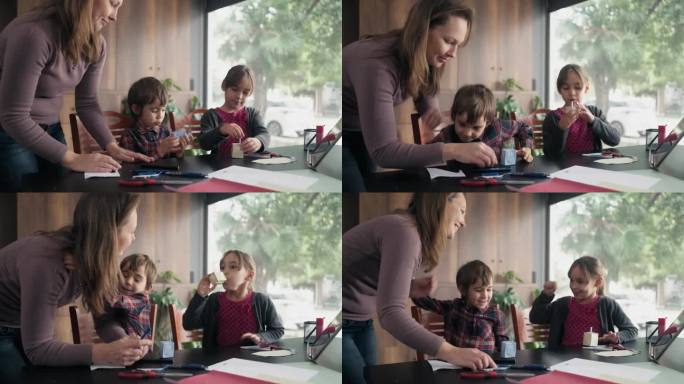 孩子们和妈妈用彩色纸做折纸玩具，按照数码平板电脑视频教程中指示的步骤