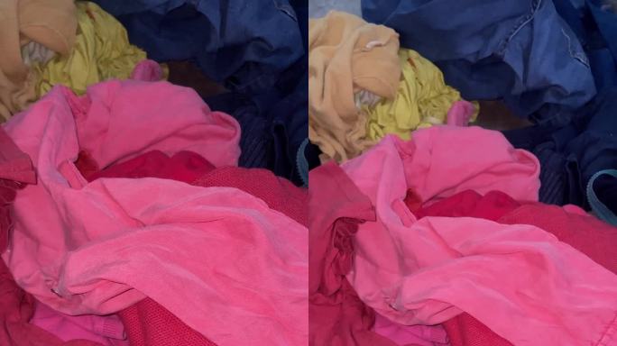 史诗缩放垂直鸟瞰镜头在一堆五颜六色的纺织废料。由于缺乏回收利用，二手衣服引发了全球变暖问题