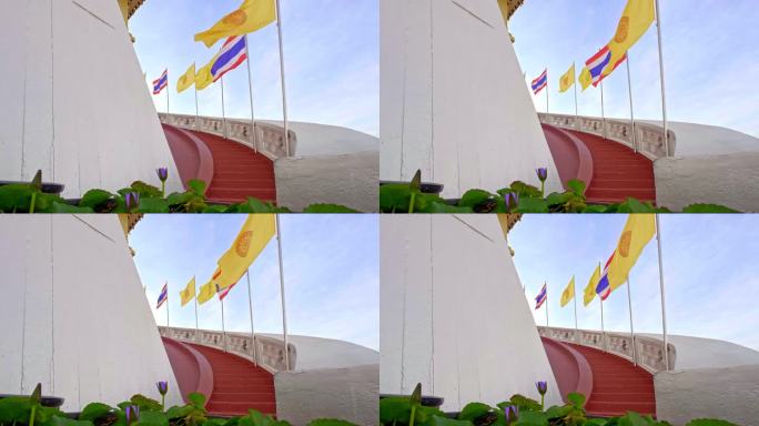 红色的楼梯上挂着泰国国旗、佛教旗和泰国皇家旗，蓝色的阳光灿烂的天空上挂着睡莲。