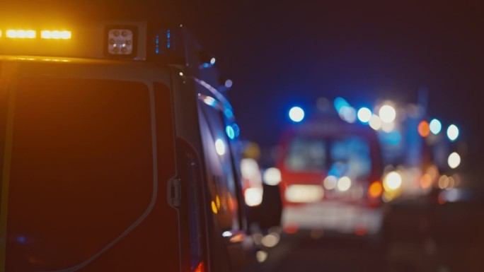 紧急服务车辆在夜间的交通中闪烁着蓝色灯和鸣笛