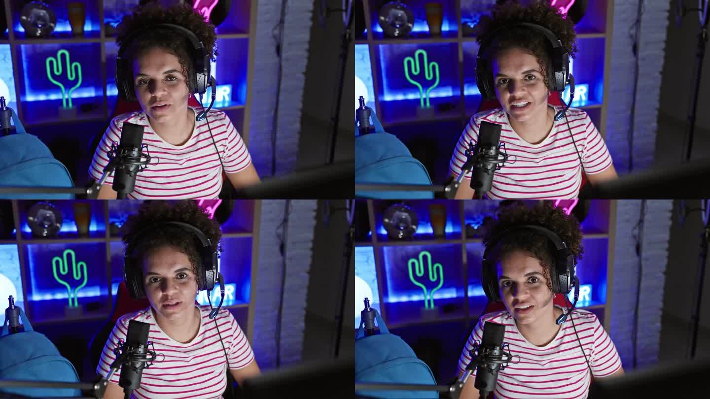 在一间霓虹灯闪烁的游戏室里，一位戴着耳机的卷发年轻女子对着麦克风说话。