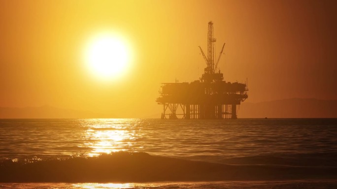 夕阳落在海上石油平台后面