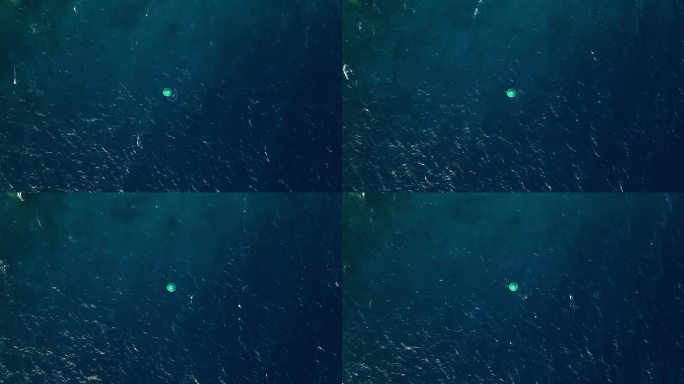 航拍无人机在开阔的绿蓝色梯度海水中俯首向下的浮标