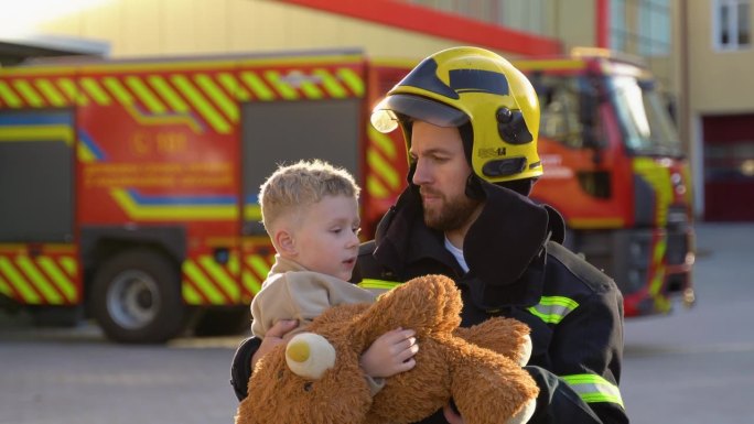 身着制服的消防员抱着获救的小男孩