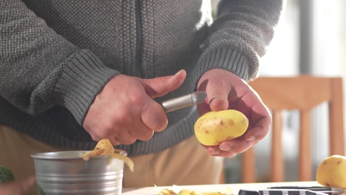 一个男人在家削土豆皮