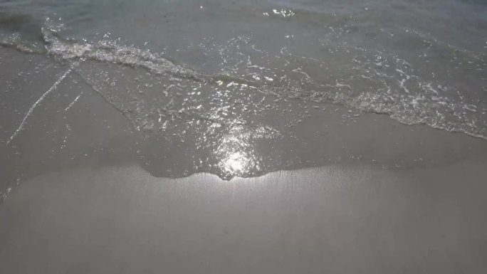 海水在岸边荡起涟漪，打在白色的沙滩上。