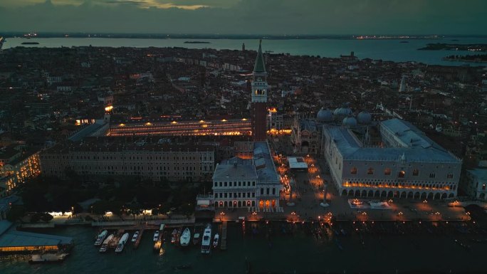 航拍实时镜头俯瞰圣马可广场与圣马可大教堂和人群游客散步和观光在城市的主要公共广场在夜晚，威尼斯，意大