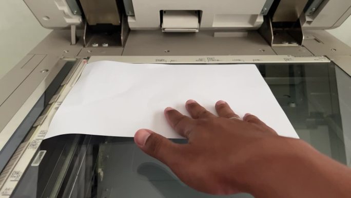 人们的手把纸放在复印机上。复印过程