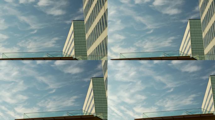 一幢现代办公大楼的一角，蓝天上飘着缕缕白云