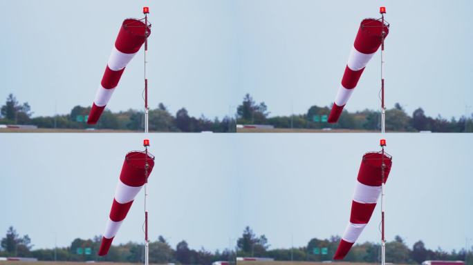 查看带有红白条纹的风袜。显示风向和风速。锥风指示器在蓝天背景下发展