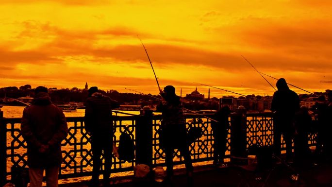 在金色的夕阳下，人们在加拉塔桥上快乐地钓鱼