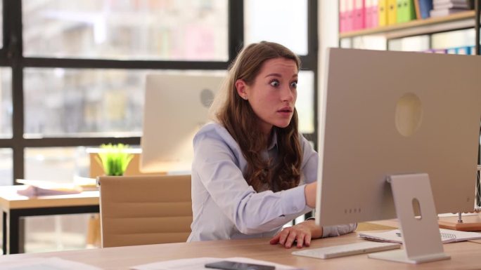 年轻漂亮的女人看着办公室的笔记本电脑，失望和震惊，并在网上阅读坏消息