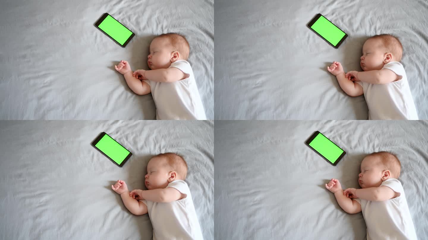 一个可爱的婴儿睡在他的婴儿床旁边的电话，色度键。一首催眠曲正在奏响，哄婴儿入睡。睡眠,童年。