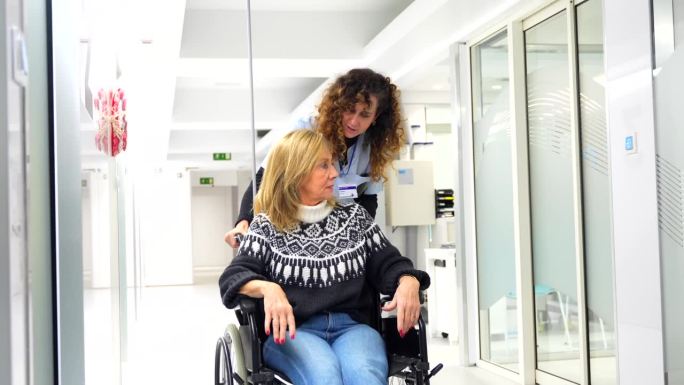 护士在医院里抬着一个坐轮椅的女人