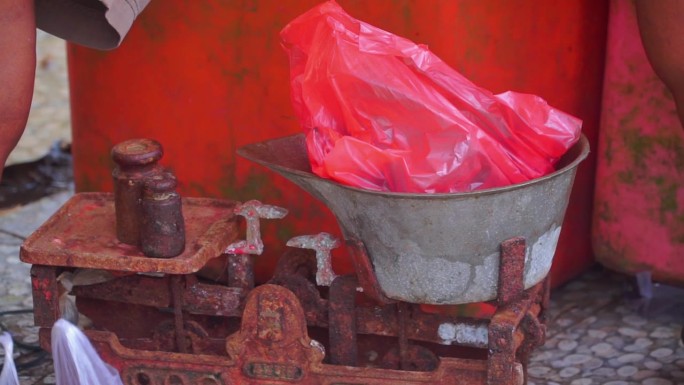 塑料袋上的物品用老式铁制秤称重——印尼传统市场