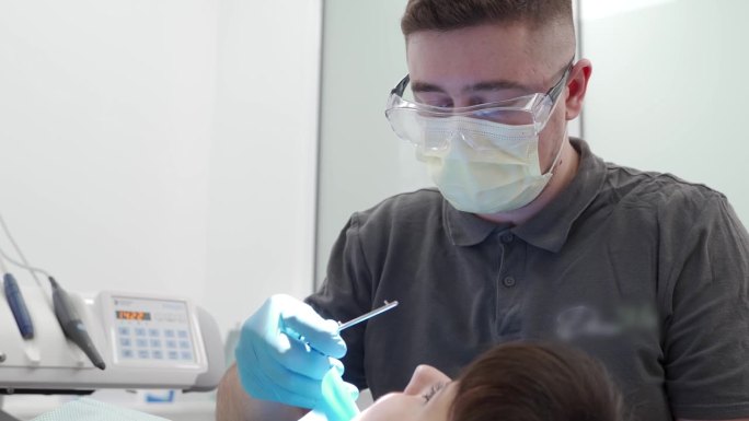 现代牙科诊所男牙医清洁根管及烧灼牙神经。口腔外科医生仔细治疗病人的牙齿。专业牙髓医生治疗根管。牙髓学