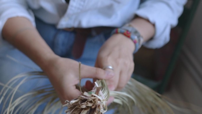 一个女孩用干草编了一条辫子。手做针线活的特写。体力劳动，小生意，家庭和睦。
