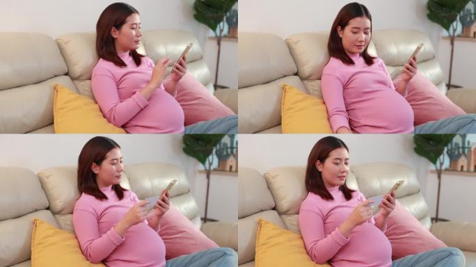 亚洲孕妇坐在沙发上，在家用手机享受网上购物