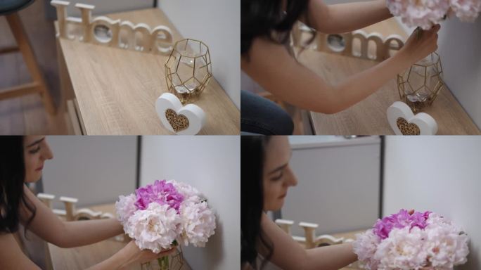 一个女孩把粉红色和白色的牡丹放在一个玻璃花瓶里，放在一个现代客厅的木制床头柜上。一个留着黑色长发的女