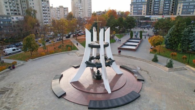 秋季在阿富汗苏联战争中牺牲的摩尔多瓦士兵纪念碑的全景鸟瞰图。多处办公楼，住宅楼，背景中有汽车行驶。摩