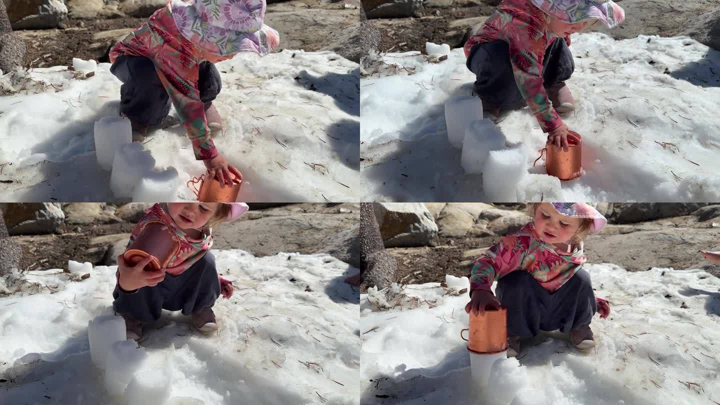 初学走路的孩子在春天的雪地里拿着杯子玩耍