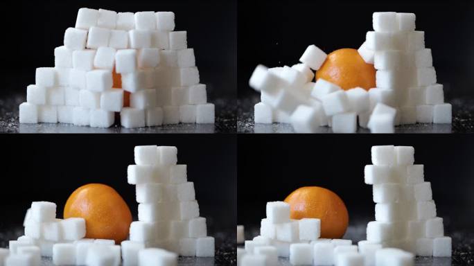 慢动作橙子冲破白糖方块堆叠的墙。选择健康的生活方式。不健康饮食的概念，糖尿病，肥胖，心脏病。甜食上瘾