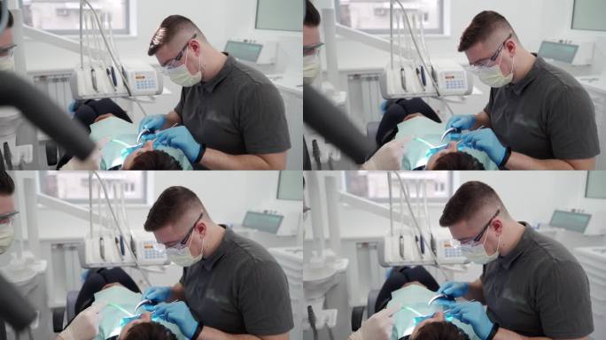 在现代牙科诊所工作的牙医和助理。医生取出牙齿上的结石和硬菌斑，助手手持唾液喷射器。口腔医生为病人做手