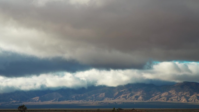 戏剧性的天空在山脉和沙漠土地的前景，时间流逝