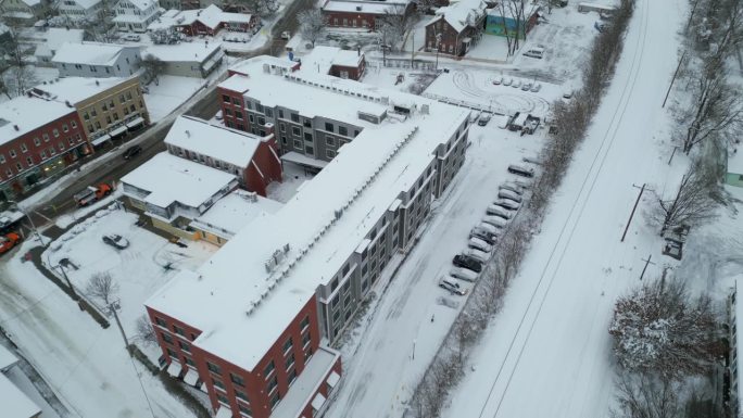 无人机倾斜显示市区主要街道在暴风雪后清理道路的铲雪车