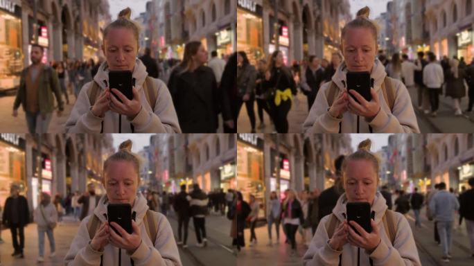 在繁忙的街道上，手持智能手机的女游客挤在人群中