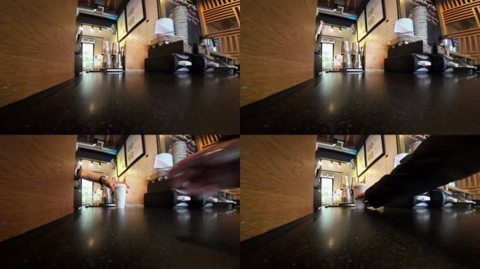 在星巴克，一个人伸手去拿外卖杯，从低角度拍摄。